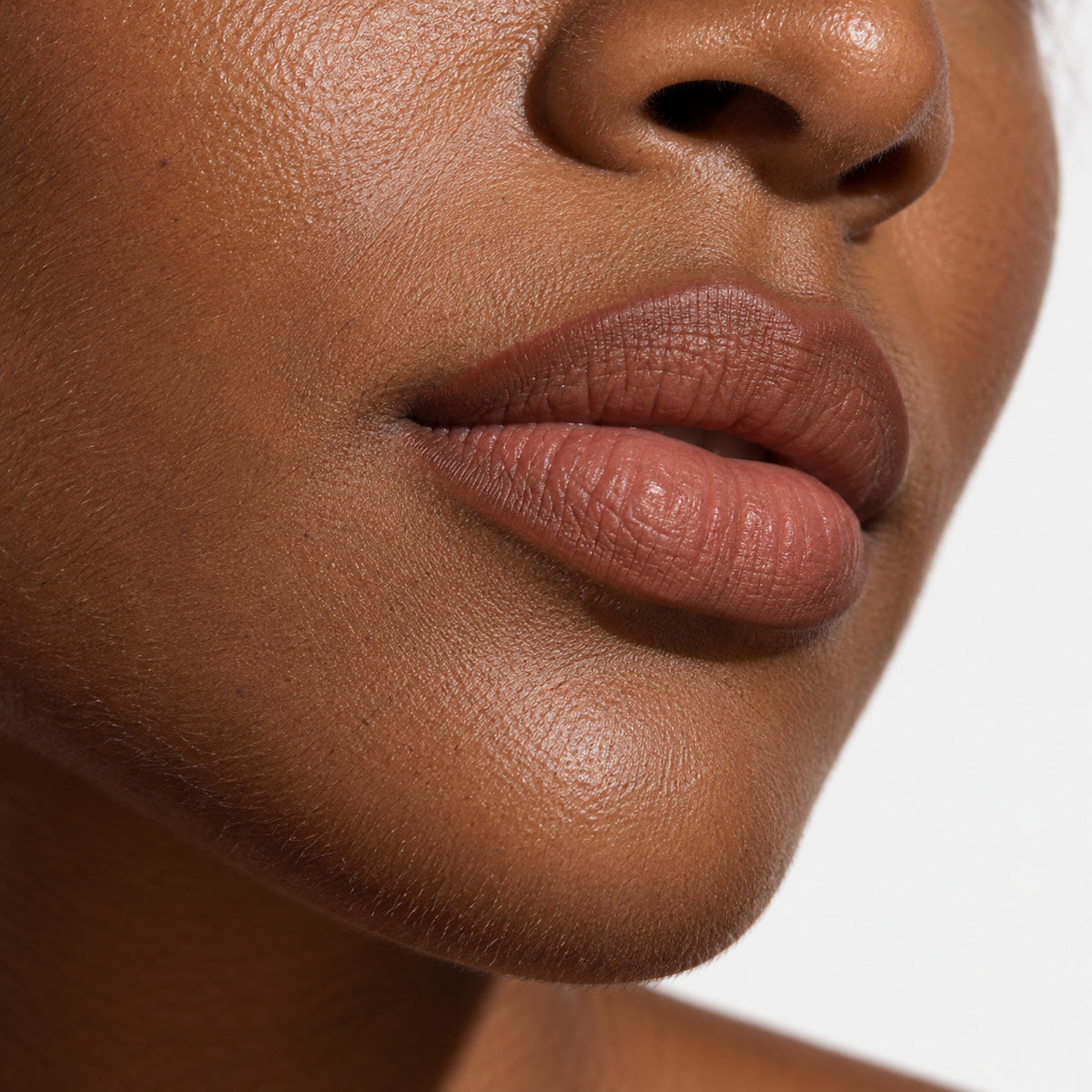 Close-up of lips lined in a warm nude tone with the lip edge softly defined