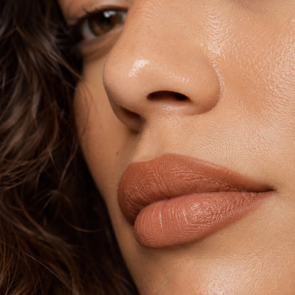 Close-up of the creamy retractable lip liner drawing along the lower lip in a nude-pink shade