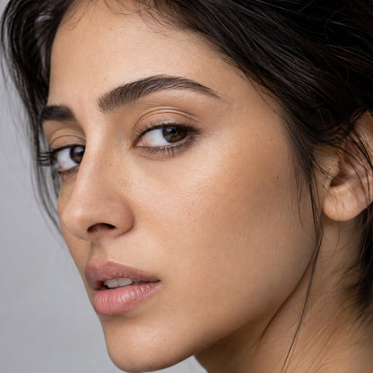 Close-up of a groomed dark brown brow and hazel eyes on medium skin